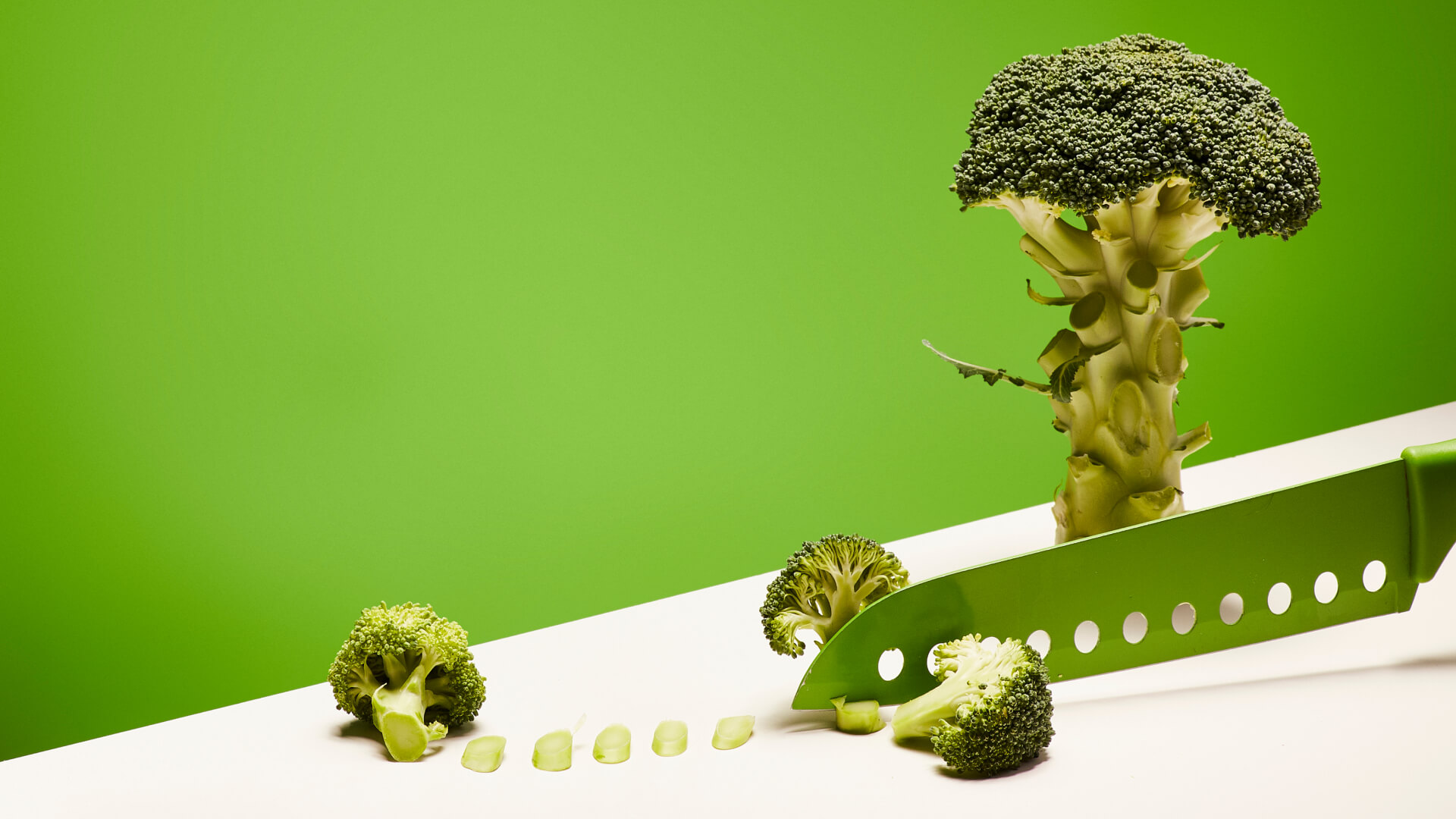 Fotografia kulinarna – scena krojenia brokuła na zielonym tle